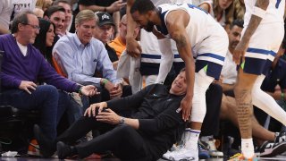 Head coach Chris Finch of the Minnesota Timberwolves grabs in leg in pain after a collision with Mike Conley #10